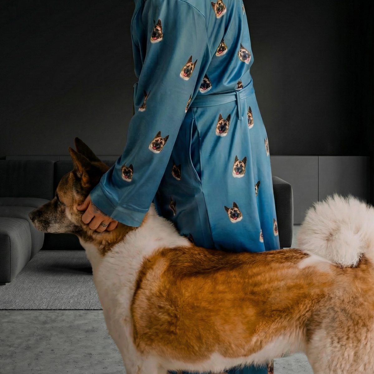 Person in a blue robe with dog patterns standing next to a dog in a living room.