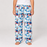 A person wearing light blue pajama pants with a repeating print of Dalmatian dogs in square panels, standing against a light gray studio background.