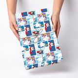 A person holds a wrapped gift box with a blue and white penguin-themed wrapping paper, tied with brown twine, against a light gray background.