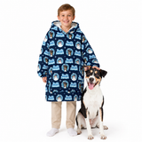 A child wearing a navy blue hooded sweatshirt with a repeating 'Just Dog' dog print stands next to a black, white, and tan dog on a plain white studio background.