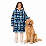 A young girl wearing a navy blue hooded sweatshirt with a repeating cartoon dog pattern stands next to a golden retriever dog on a plain white studio background.
