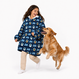 A young girl wearing a navy blue hooded blanket sleeper with a repeating Texas Longhorns logo pattern is playfully chasing a golden retriever dog on a seamless white background.
