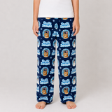 A person wearing navy blue fleece pajama pants with a repeating 'Frosty Snowman' cartoon pattern, standing barefoot against a light gray studio background.