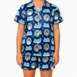 A child wearing a matching short-sleeve button-up pajama shirt and shorts set in navy blue with a repeating 'Frosty Snowman' dog print, shown against a plain white background.