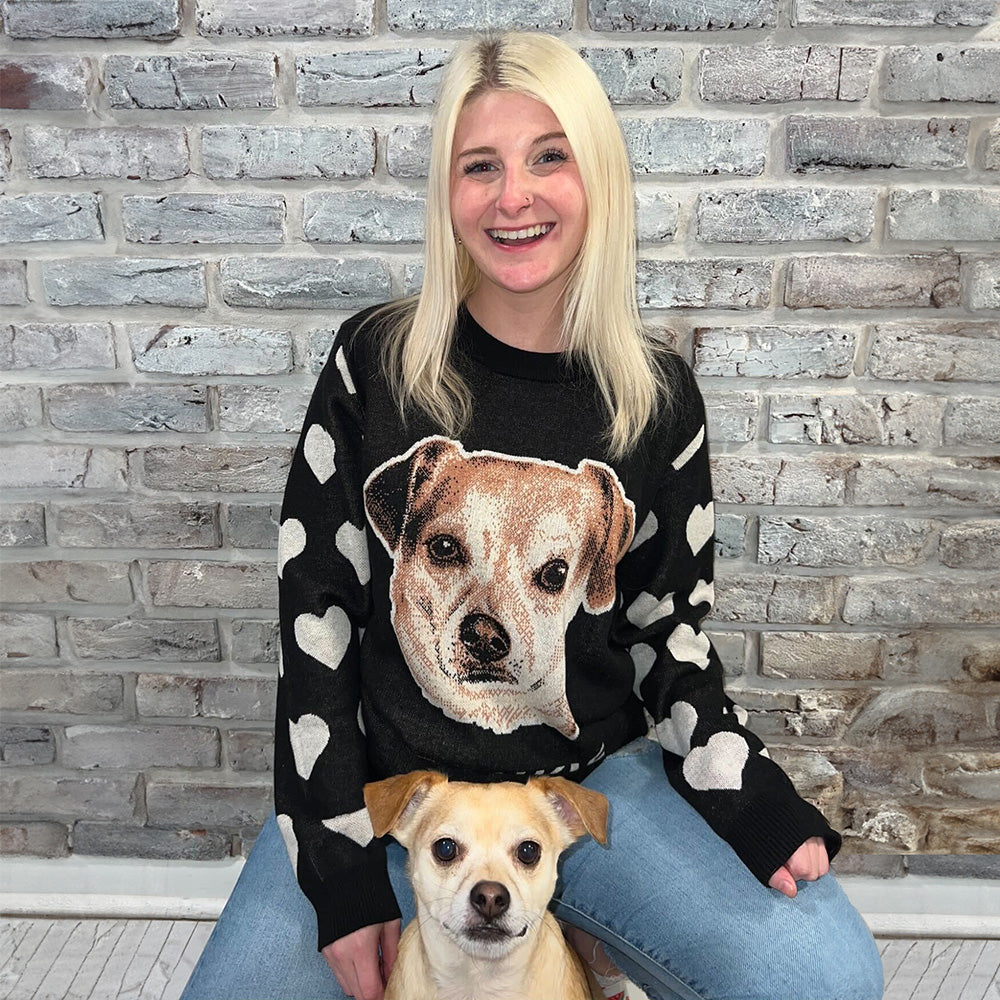 Woman with sweater with hearts sleeves and a dog print on the center with her dog.