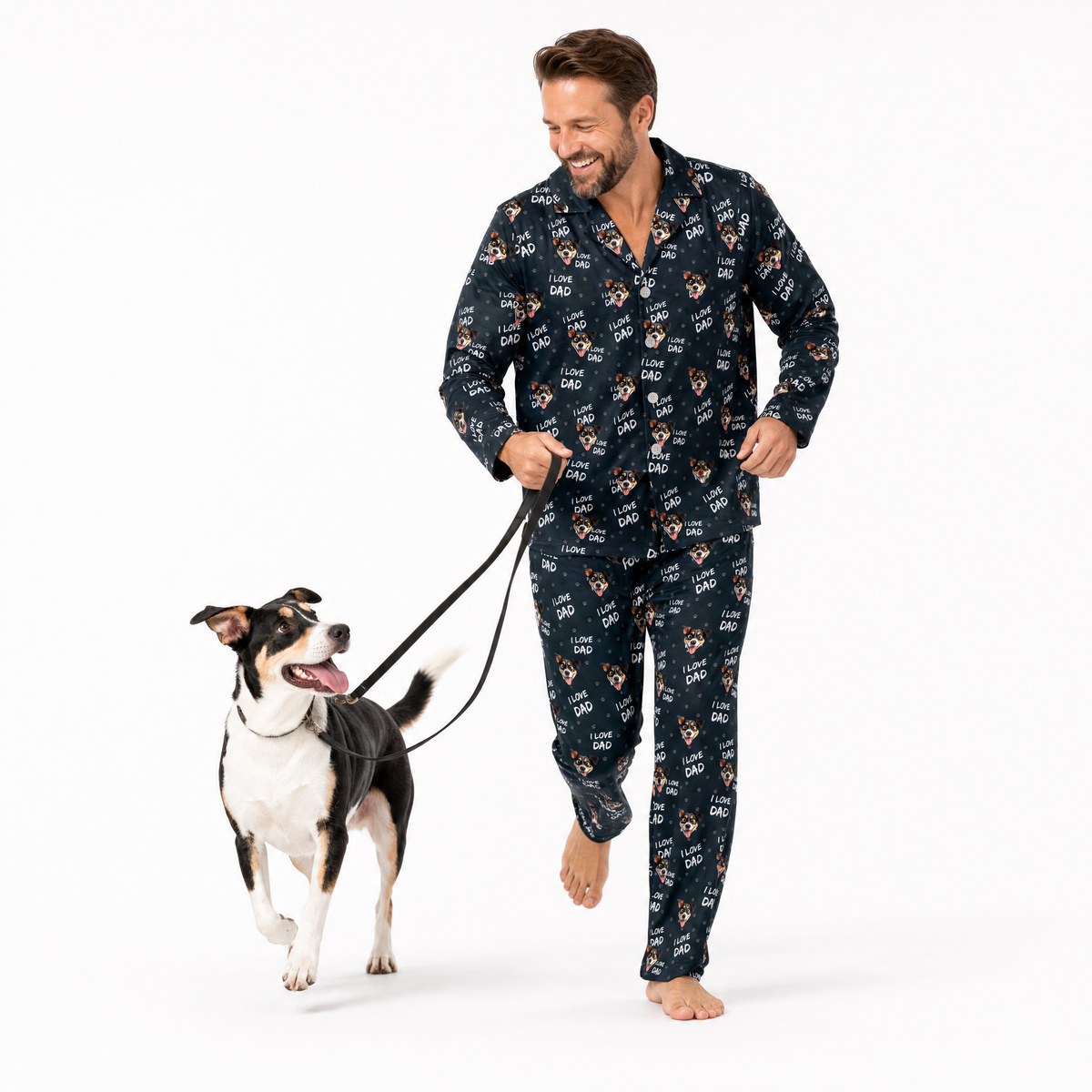 Man wearing navy pajamas with dog pattern walking a dog on a white background