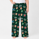 A person wearing dark green Christmas-themed lounge pants with a dog print, standing against a light gray studio background.