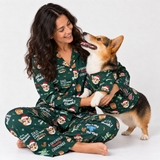 A woman and a corgi dog wearing matching dark green Christmas-themed pajamas with a dog print, sitting together against a plain white studio background.