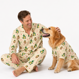A man and his golden retriever dog are both wearing matching cream-colored pajamas with a green and red cartoon cactus pattern, posed against a clean white studio background.