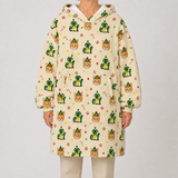 A person wearing a hooded fleece pullover with an all-over Christmas elf print, paired with light beige pants, against a plain light gray studio background.