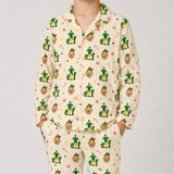 A person wearing a matching long-sleeve pajama set with a repeating Elf on the Tree pattern on a light cream background. The pajamas feature green elf figures, candy canes, ornaments, and small red accents.