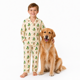 A young boy wearing a cream-colored pajama set with a green and brown cactus pattern stands next to a golden retriever dog on a solid white background.