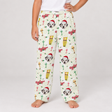 A person wearing cream-colored Christmas-themed pajama pants with a print of Dalmatian dog faces in Santa hats, green ornaments, and red ornaments, shown against a light gray studio background.