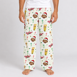 A person wearing cream-colored pajama pants with a festive Christmas dog print, standing barefoot against a light gray studio background.