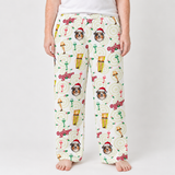 A person wearing holiday-themed lounge pants with a repeating print of a dog's face, cocktail glasses, Christmas trees, and 'O'Reilly' logos on an off-white background, shown against a light gray studio backdrop.
