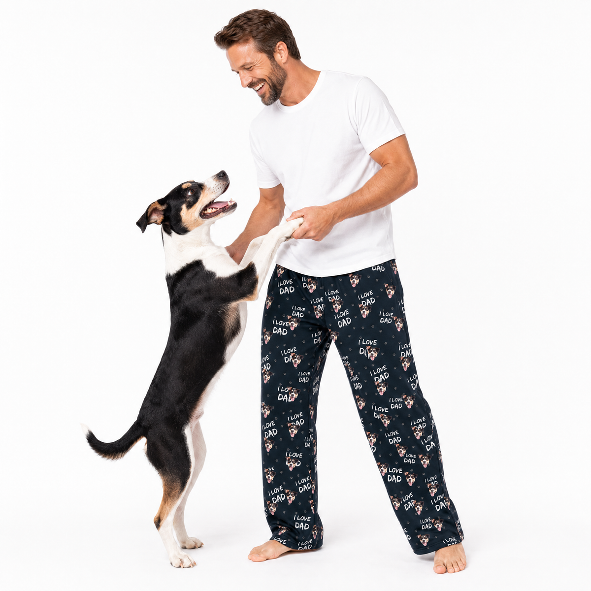 Man wearing black 'I love dad' pajama pants standing with a dog on a white background