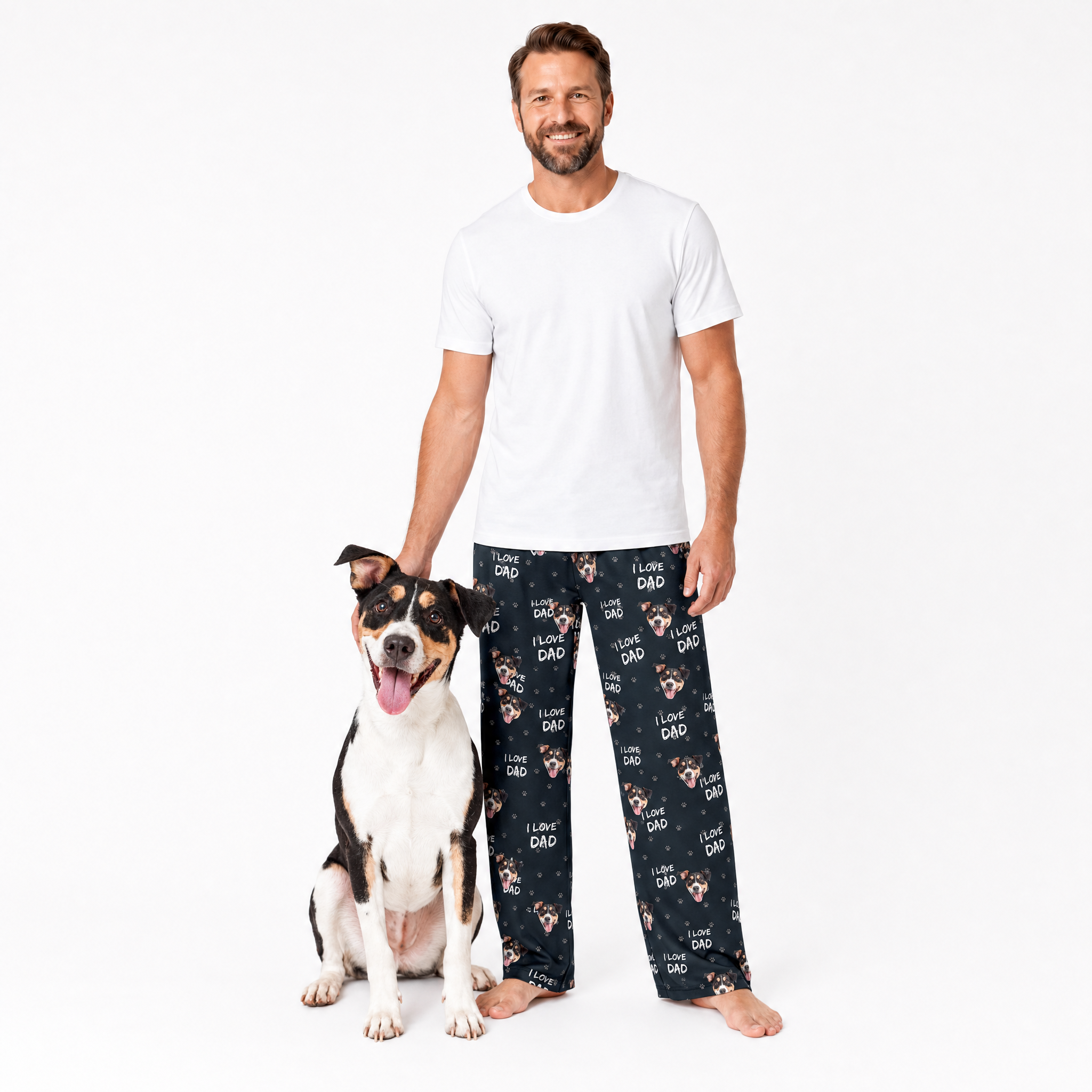 Man wearing black pajama pants with dog pattern standing next to a dog on a white background