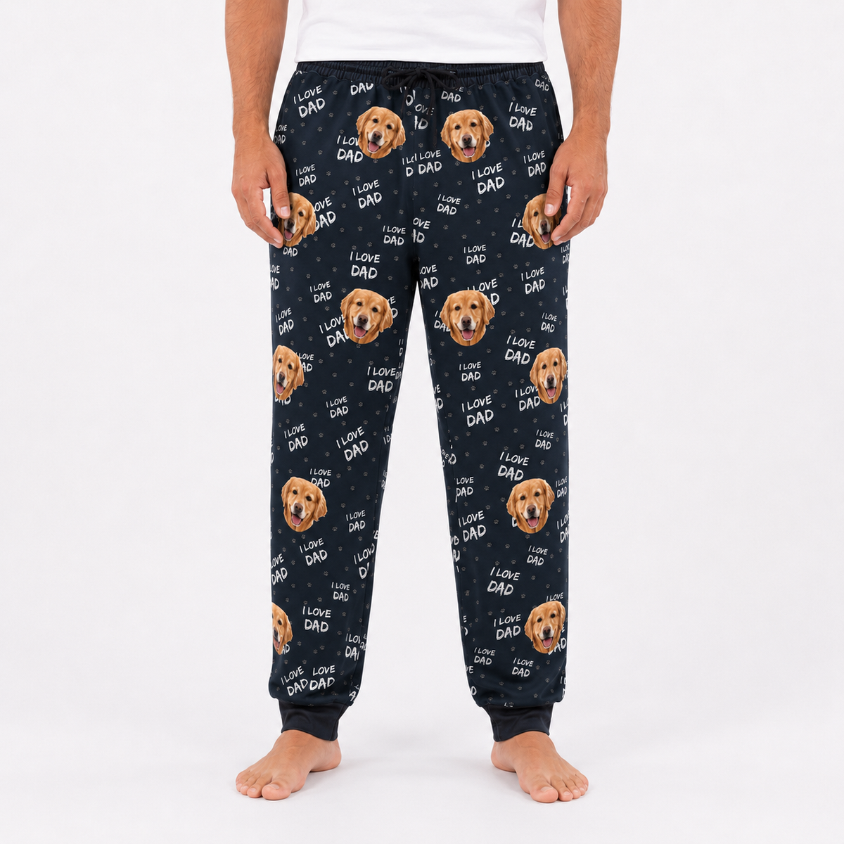 Close-up of black sweatpants with repeating golden retriever face and I Love Dad text pattern, worn by man