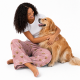 Person in “I Love Mom” pajamas hugging a golden retriever on white background.
