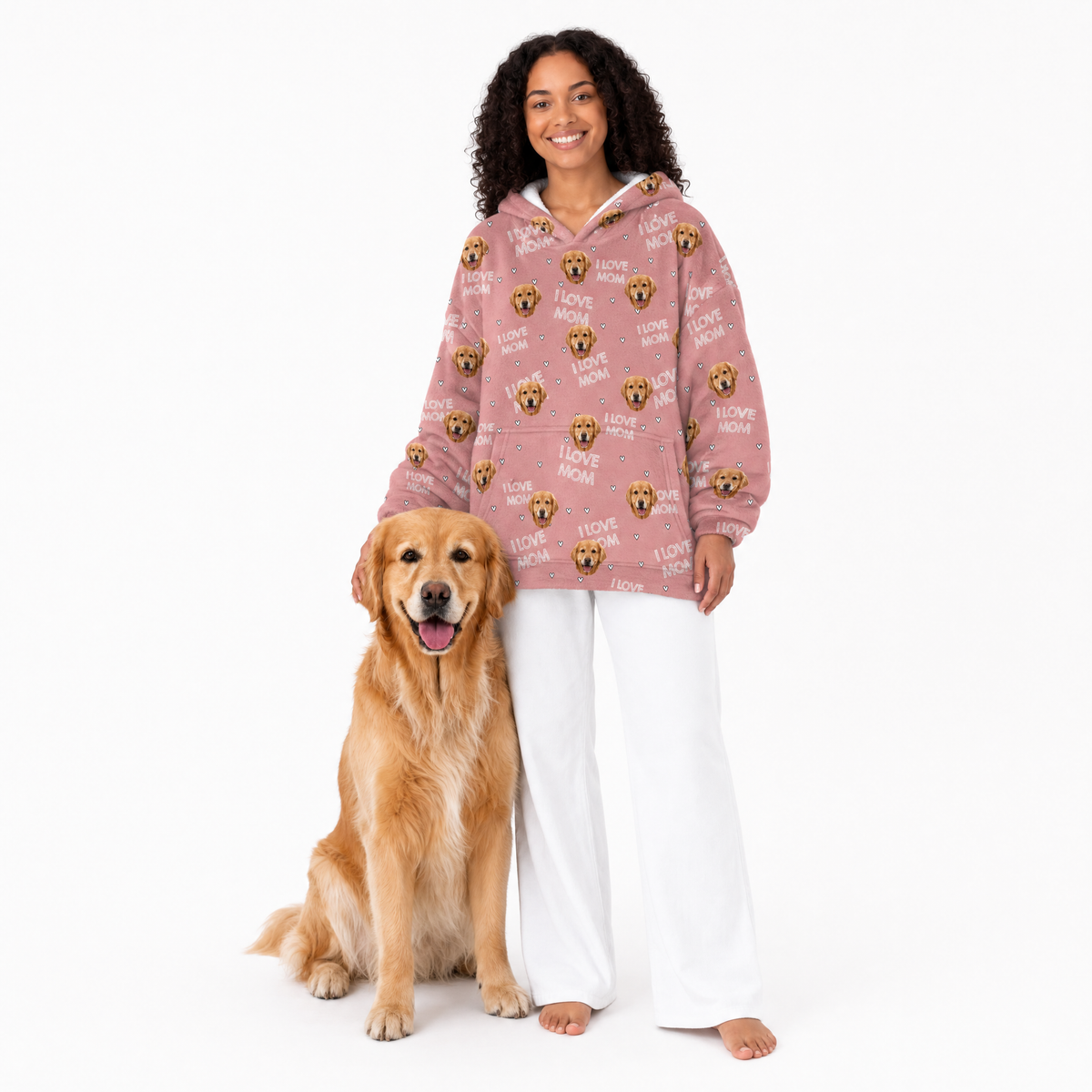 Woman wearing a pink blanket hoodie with dog pattern and a dog standing next to her on a white background