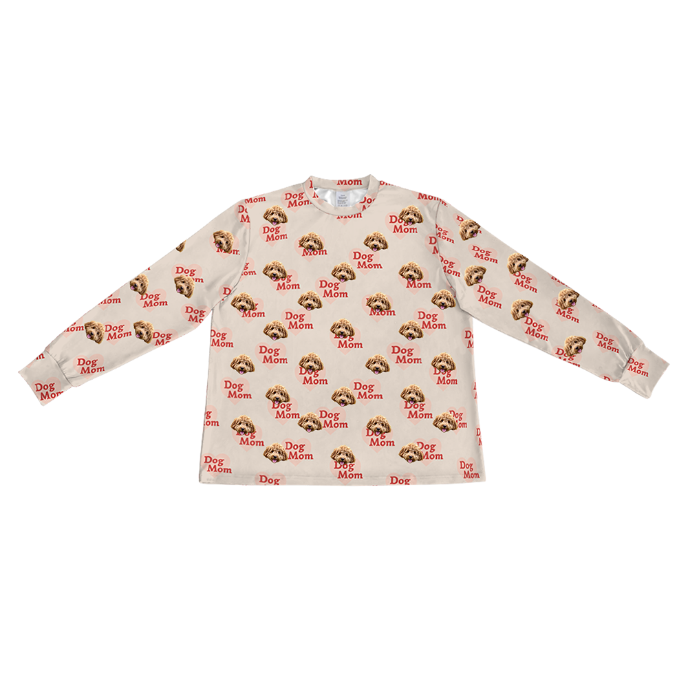 A light tan long-sleeve pajama top with a crew neck. It features a repeating custom pattern of a light brown Goldendoodle's face, interspersed with graphics of reddish-brown hearts that contain the red text "Dog Mom".