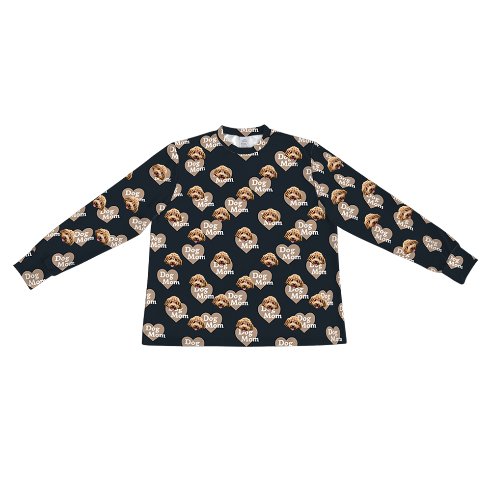 A light tan long-sleeve pajama top with a crew neck. It features a repeating custom pattern of a light brown Goldendoodle's face, interspersed with graphics of reddish-brown hearts that contain the red text "Dog Mom".