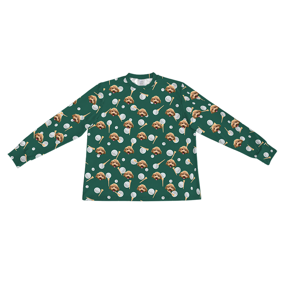 A dark green long-sleeve pajama top with a crew neck. It features a repeating custom pattern of a light brown Goldendoodle's face, interspersed with graphics of white dimpled golf balls and wooden tees.