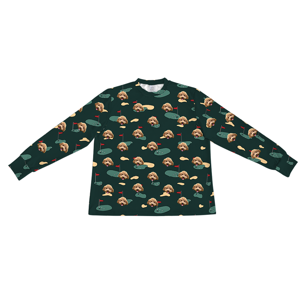 A dark green long-sleeve pajama top with a crew neck. It features a repeating custom pattern of a light brown Goldendoodle's face, interspersed with graphics of green golf greens with red flags, and tan sand traps.