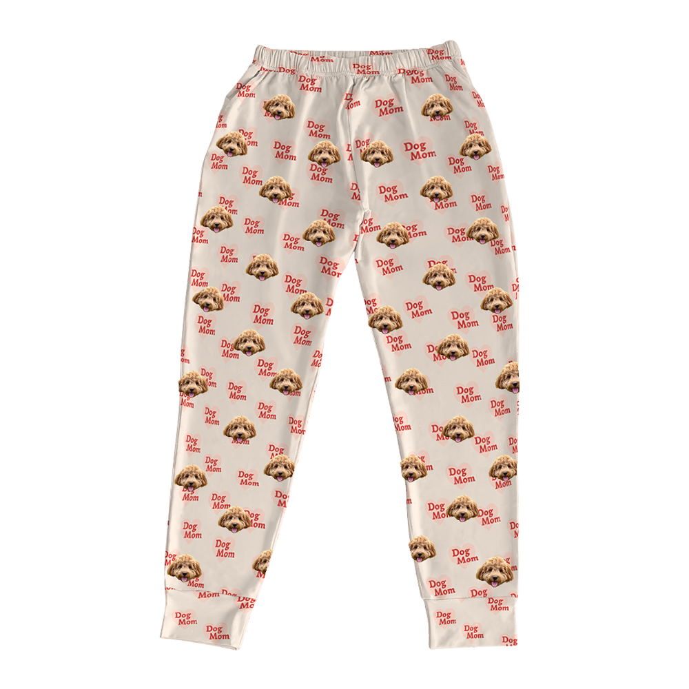 Light tan pajama joggers covered in a repeating pattern. The pattern features alternating elements: the phrase "Dog Mom" in red text, and smiling headshots of a light brown dog.