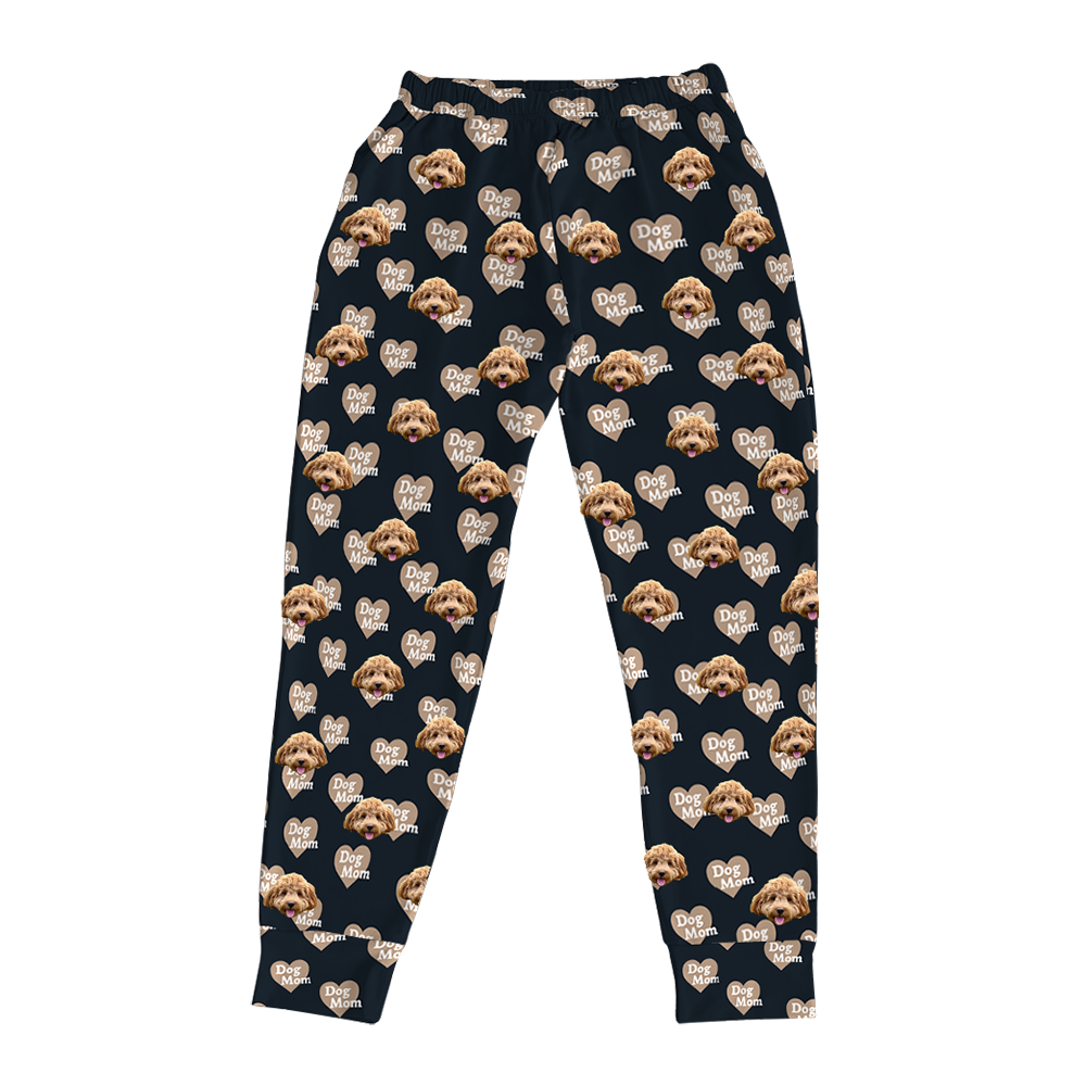 Black pajama joggers covered in a repeating pattern. The pattern features alternating light brown dog and heart shapes with the text "Dog Mom" inside.
