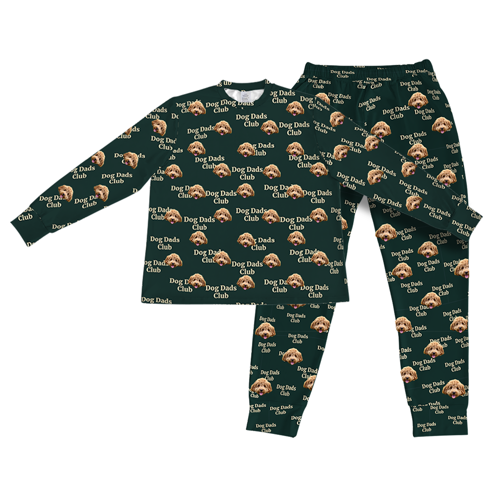 A two-piece pajama set consisting of a long-sleeve top and matching jogger pants, both in dark hunter green. They feature a repeating custom pattern of a light brown Goldendoodle's face, interspersed with the white text "Dog Dads Club" in a repeating diagonal pattern. 