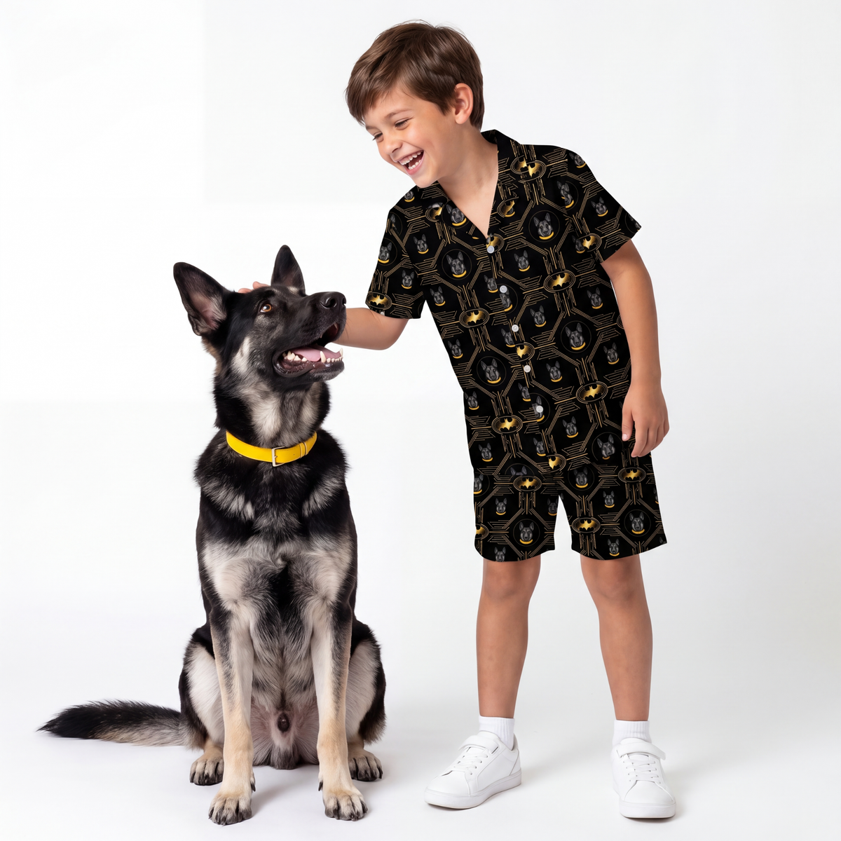 Child wearing a batman pajama set standing next to a dog on a white background