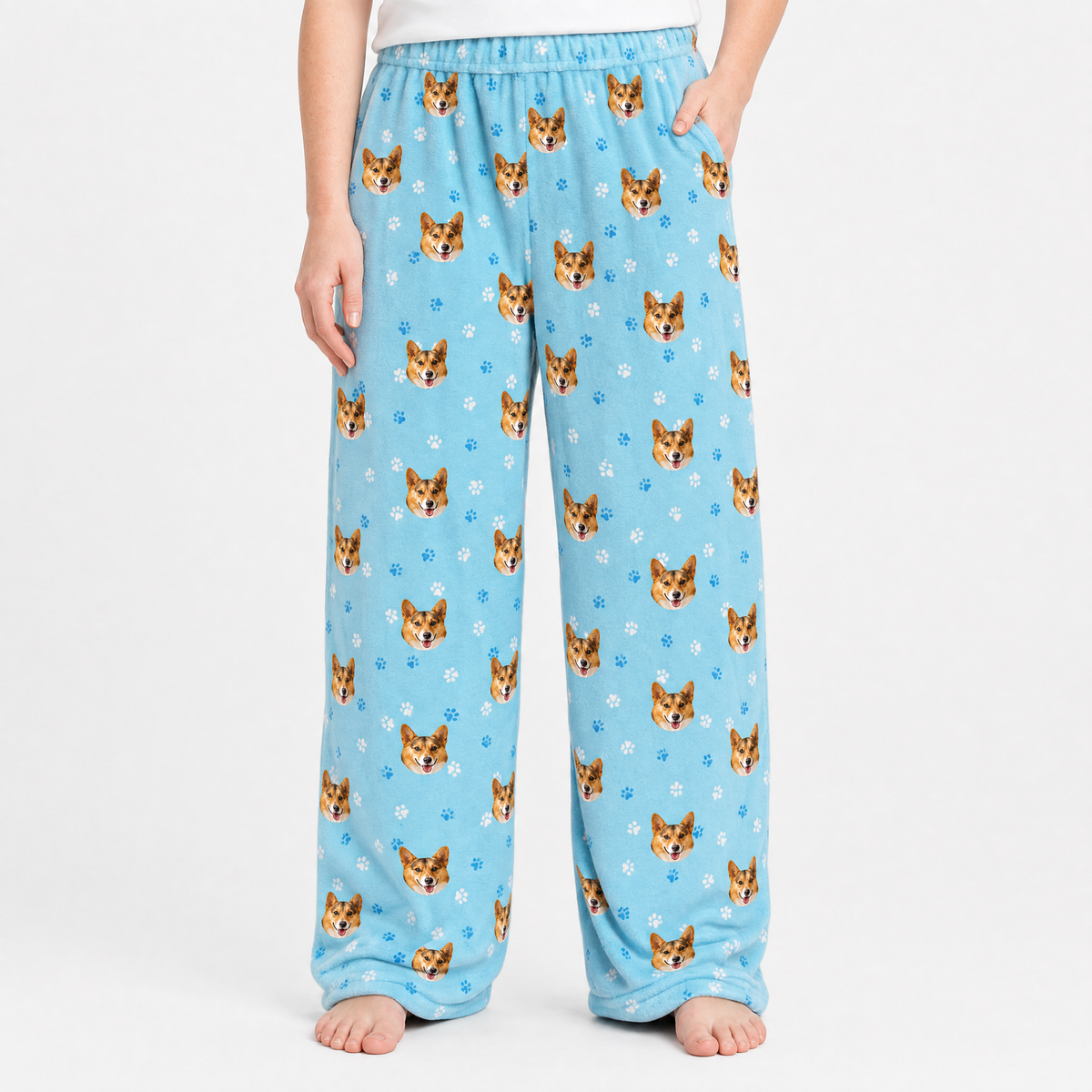 Light blue pajama pants with cat pattern worn by a person on a white background