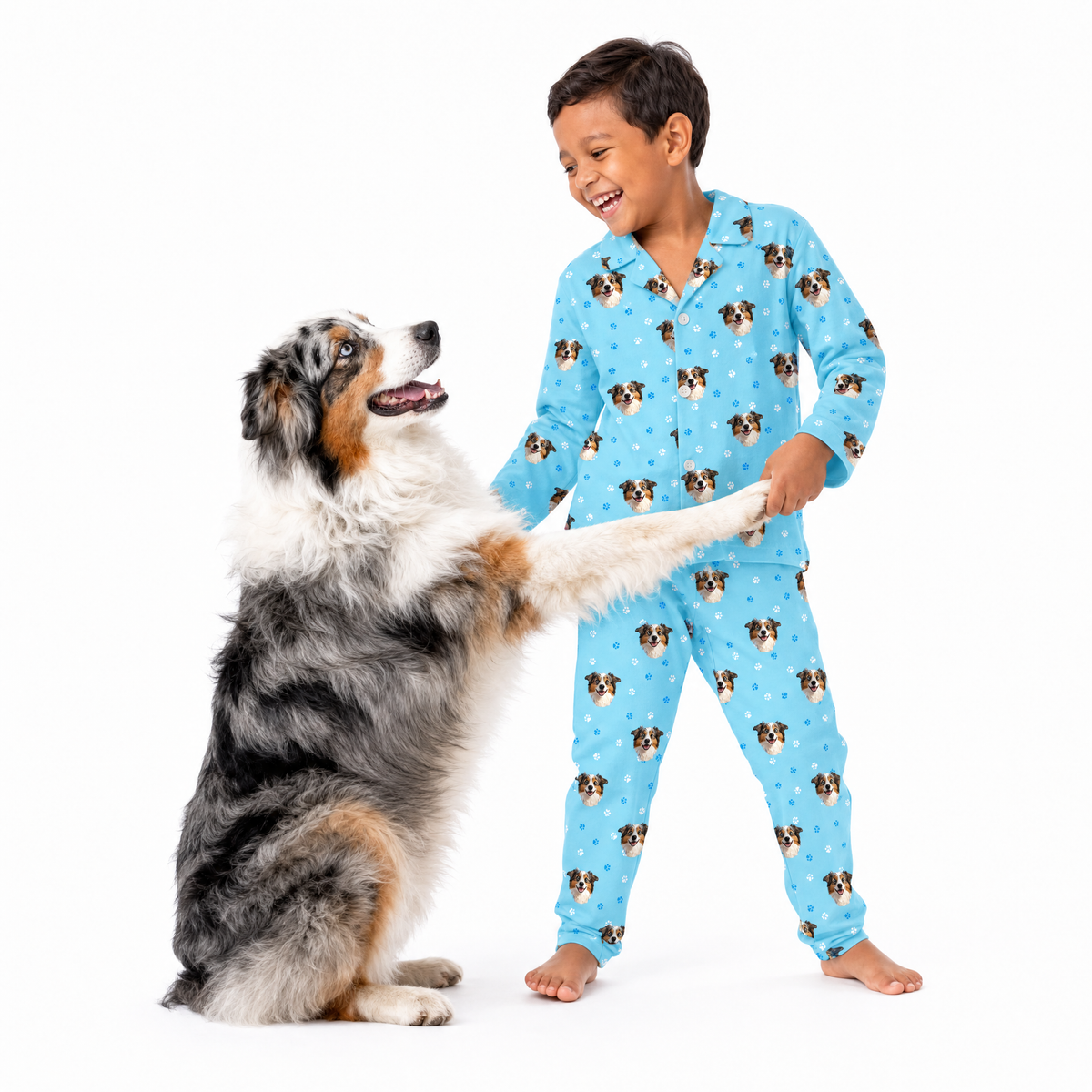 Child wearing light blue pajamas with dog pattern interacting with a dog on a white background