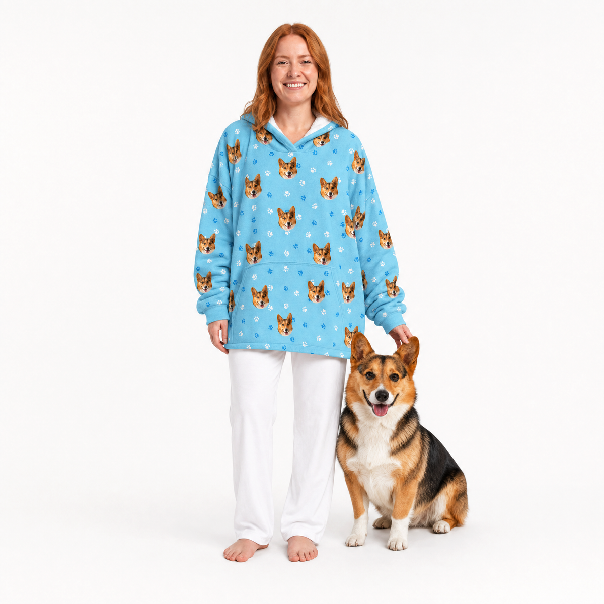 Woman wearing a light blue blanket hoodie with dog pattern standing next to a dog on a white background