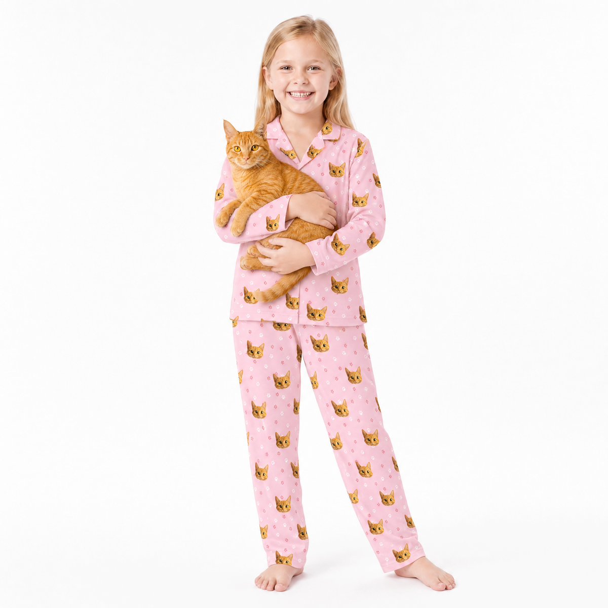 Child wearing pink pajamas with cat pattern holding an orange cat on a white background