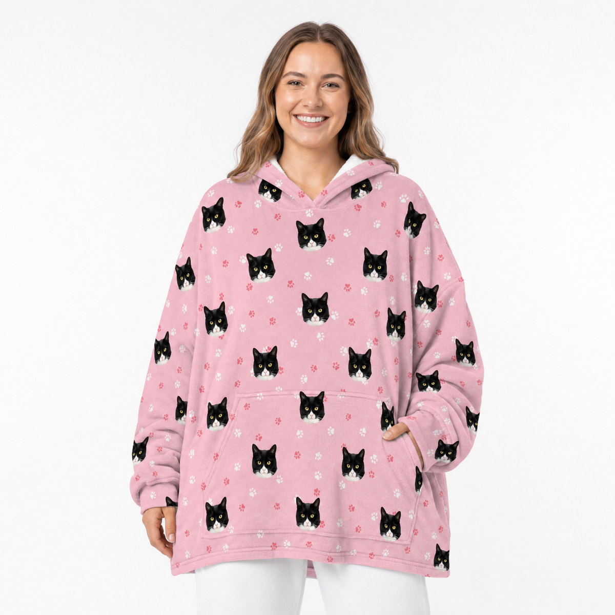 Woman wearing a pink blanket hoodie with black cat patterns on a white background