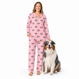 Woman wearing light pink paws pajamas with dog pattern standing next to a dog on a white background
