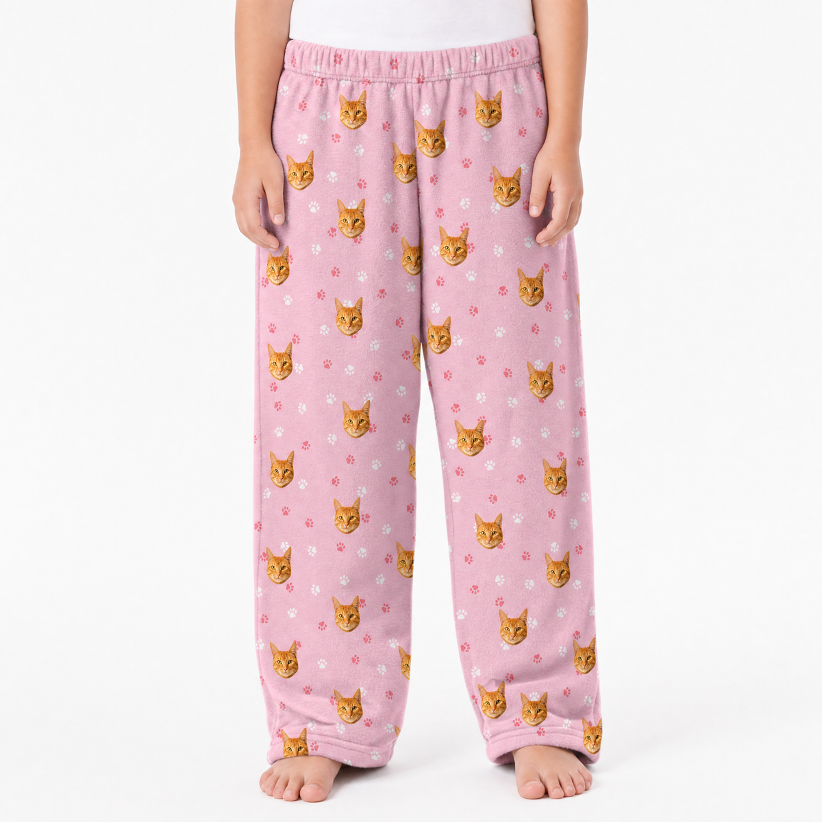 Pink pajama pants with cat pattern worn by a person on a white background
