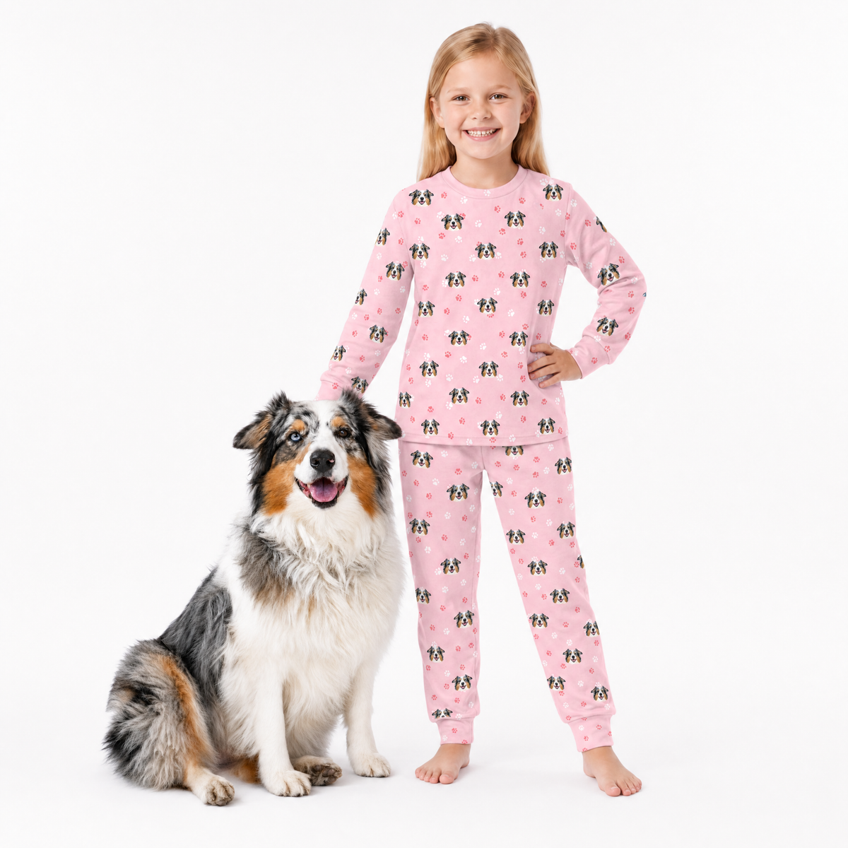 Child wearing pink jogger pajamas with a dog next to them on a white background