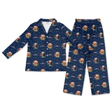A two-piece children's pajama set featuring a long-sleeve button-up top and matching pants in navy blue with an all-over Christmas dog print. The print shows golden retriever dogs wearing Santa hats under snowflakes and stars.