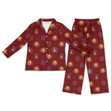 A two-piece kids' pajama set featuring a long-sleeve button-up shirt and matching pants in a deep burgundy red. The fabric is decorated with a repeating pattern of golden retriever dog faces inside circular medallions with small blue accents.