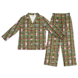 A two-piece pajama set featuring a long-sleeve button-up top and matching pants in a green plaid pattern with cartoon French Bulldog characters, pink bows, and small blue and white signs, shown on a plain white background.