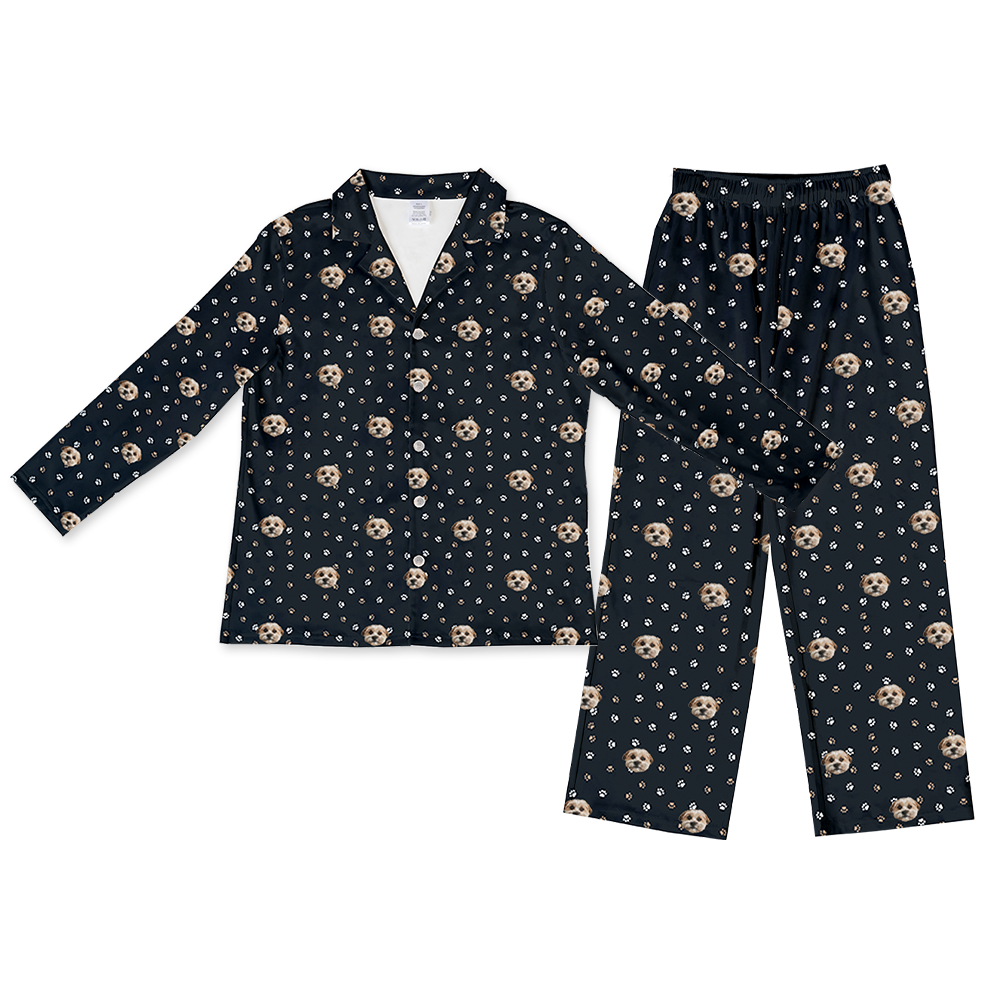 Black long-sleeve pajama set with a button-down top and matching pants, decorated with an all-over print of a single dog’s face and scattered white and tan paw prints.