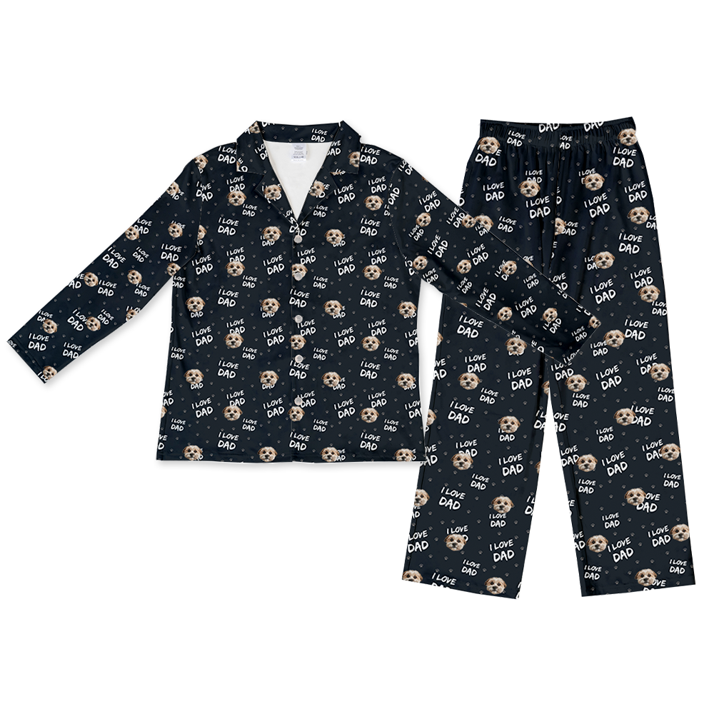 A black long-sleeve pajama set, consisting of a button-down top and matching full-length pants. Both pieces feature a repeating pattern of light brown and white dog faces, white text reading "I LOVE DAD", and small white and light brown paw prints.