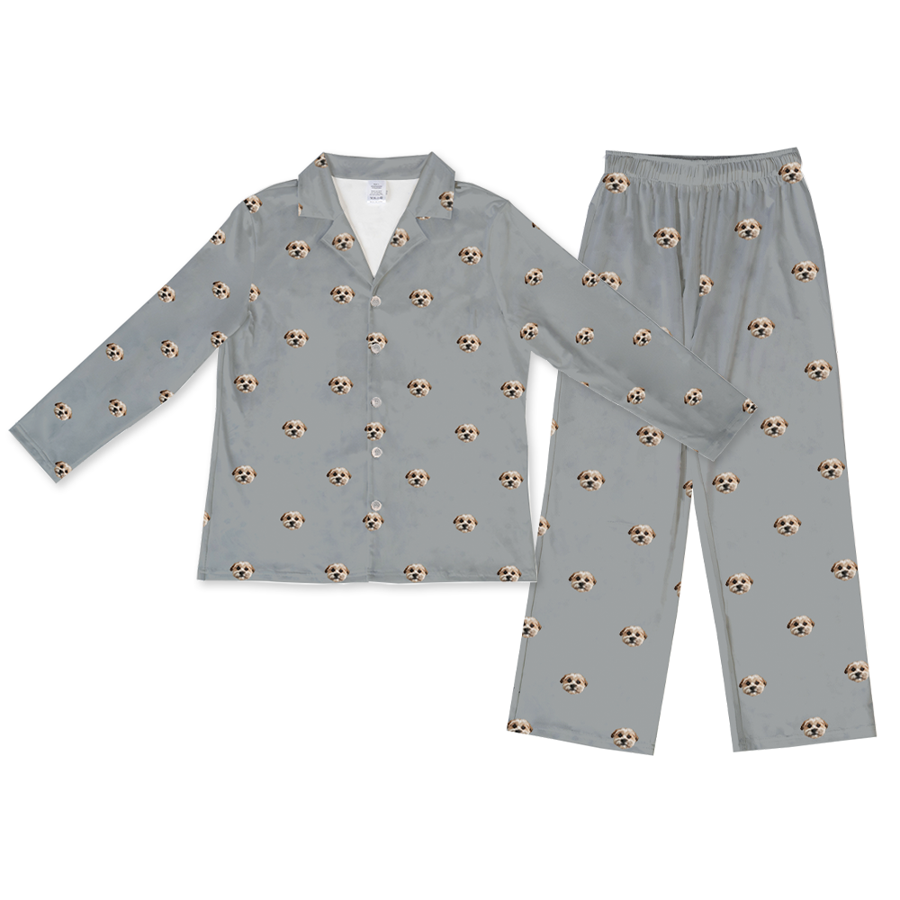 A two-piece pajama set, consisting of a long-sleeved, button-down top and matching long pajama pants with an elastic waist. Both pieces are slate grey and feature a repeated, scattered pattern of a single dog face.