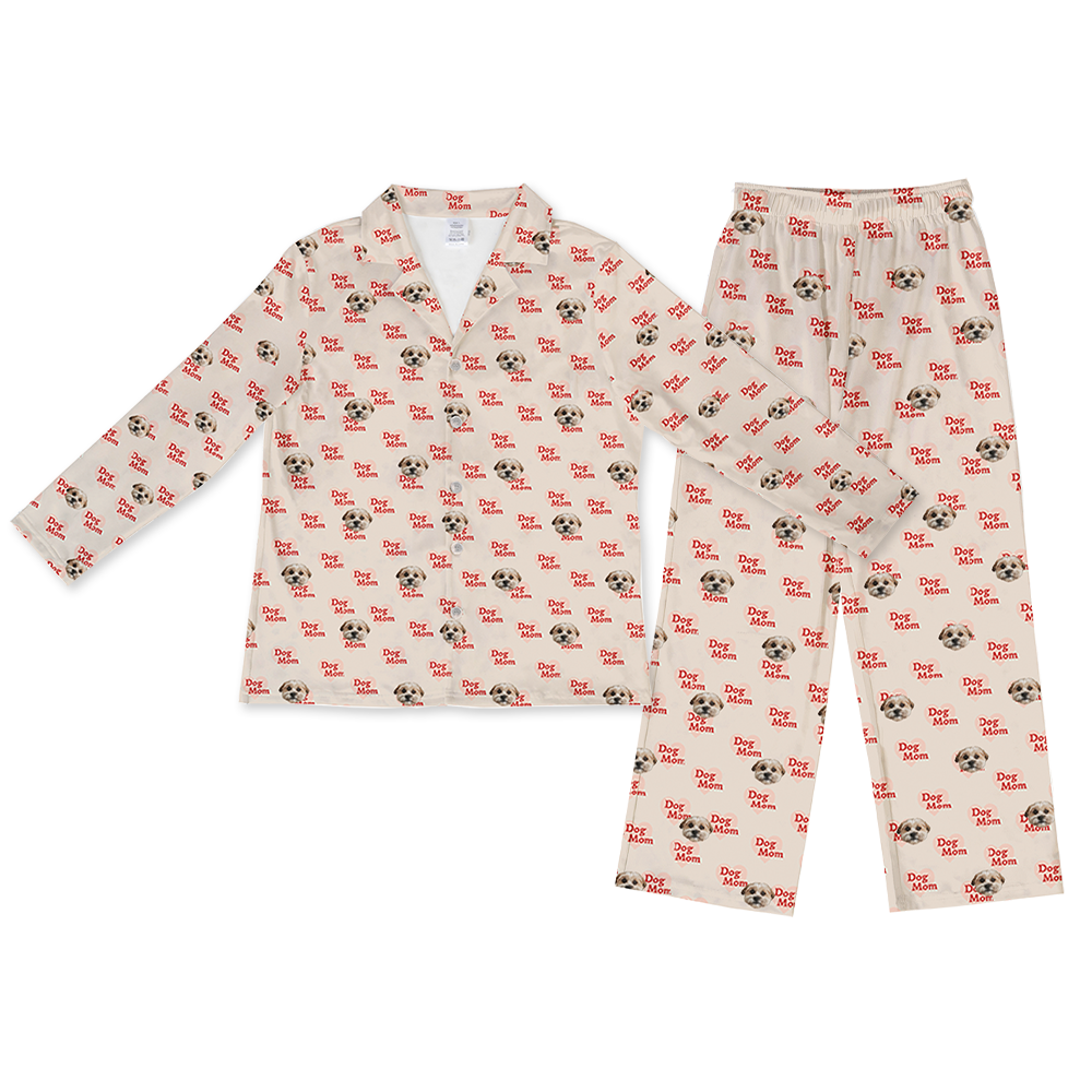Beige two-piece pajama set with a long-sleeve button-down top and matching pants, featuring an all-over pattern of dog faces and red ‘Dog Mom’ text.