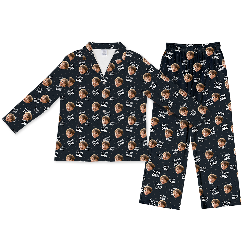 Black long-sleeve button-up pajama top with matching pants, featuring a repeating pattern of a smiling child’s face, “I LOVE DAD” text, and small heart icons scattered across the fabric.