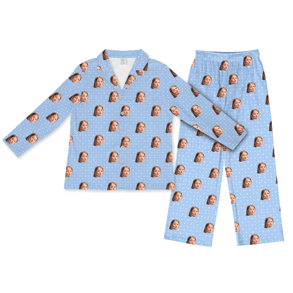 Light blue long-sleeve button-up pajama top with matching pants, featuring a repeating pattern of the same woman’s face and small white snowflakes across the fabric.