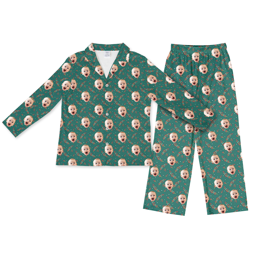 Teal long-sleeve button-up pajama top with matching pants, featuring a repeating pattern of a baby’s excited face and holiday berry sprigs across the fabric.